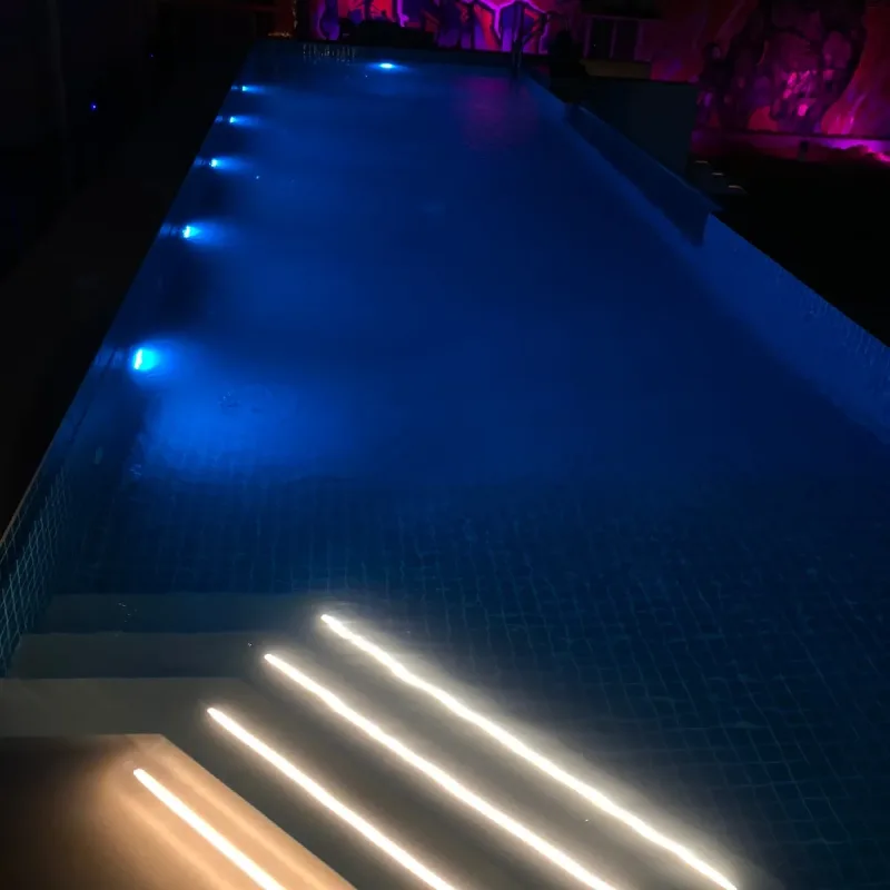 A pool lit from within after dark, the water reading as a band of blue