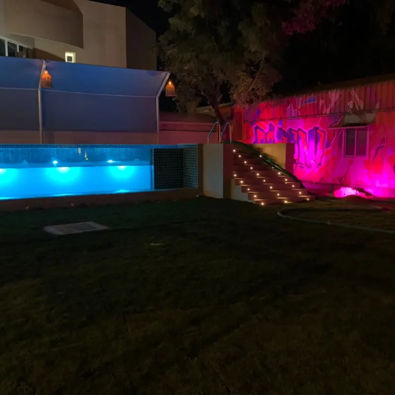 A pool lit from within after dark, the water reading as a band of blue