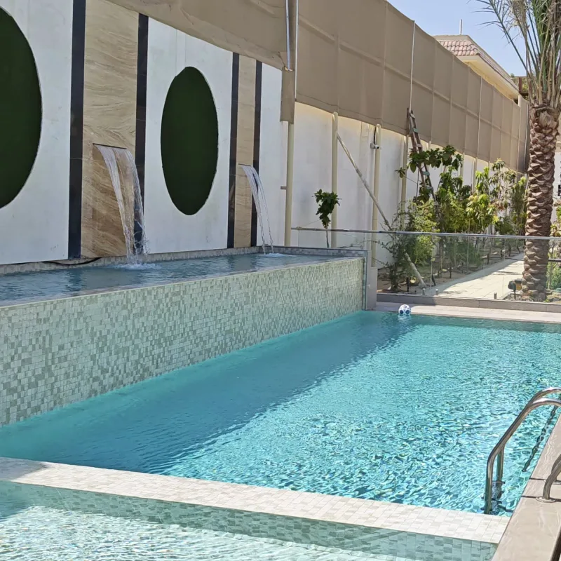 A water feature spilling into a pool beside a tiled jacuzzi