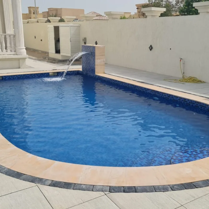 A water feature spilling into a pool beside a tiled jacuzzi