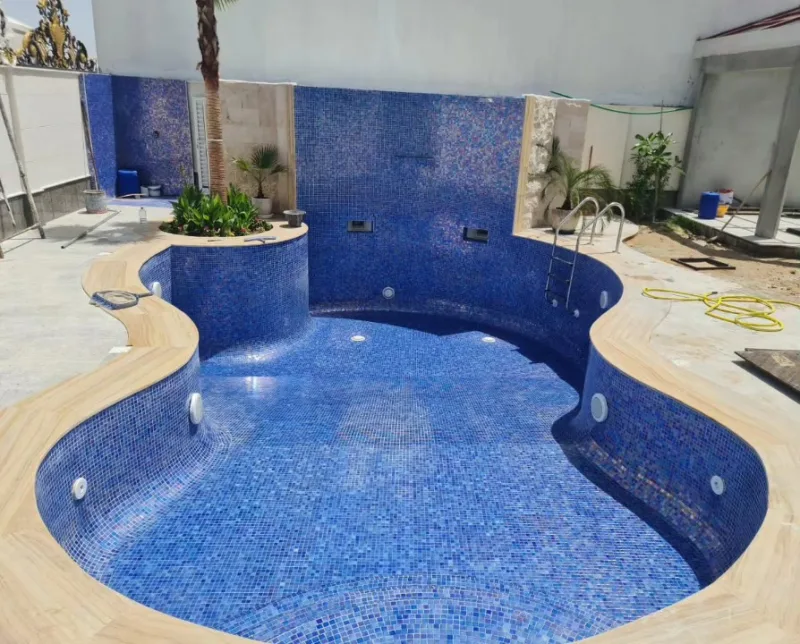 A water feature spilling into a pool beside a tiled jacuzzi