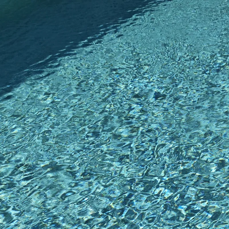 Clear, balanced pool water over pale mosaic tiling