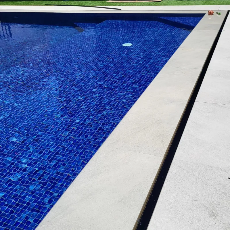A large family pool tiled in deep blue glass mosaic
