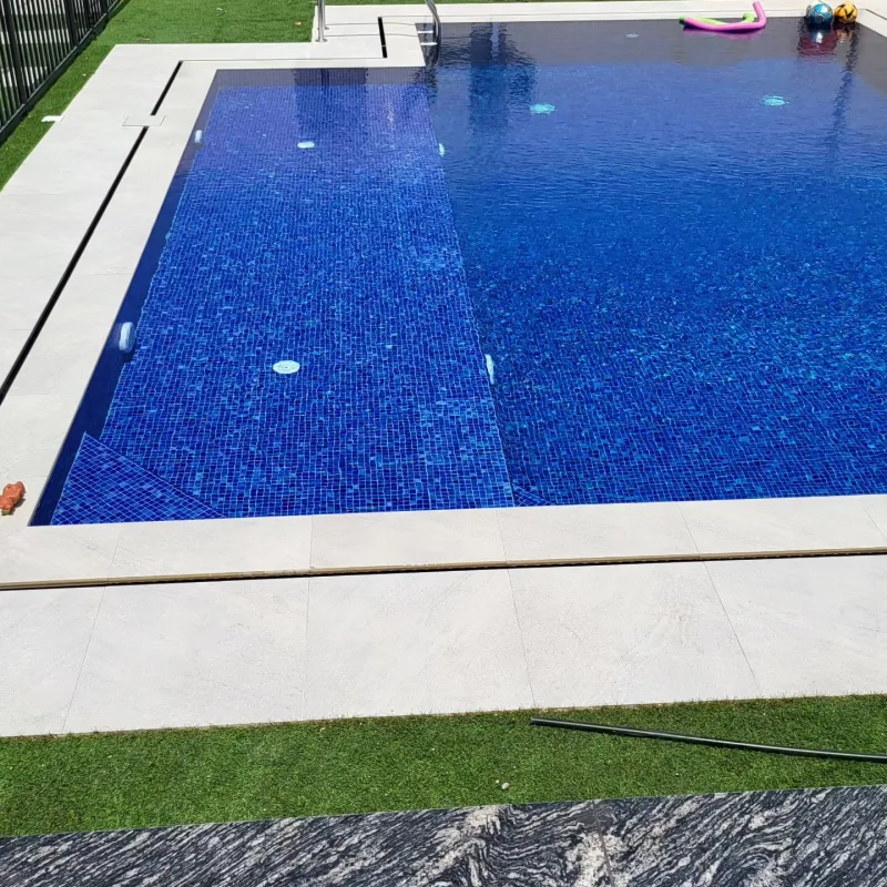 A large family pool tiled in deep blue glass mosaic