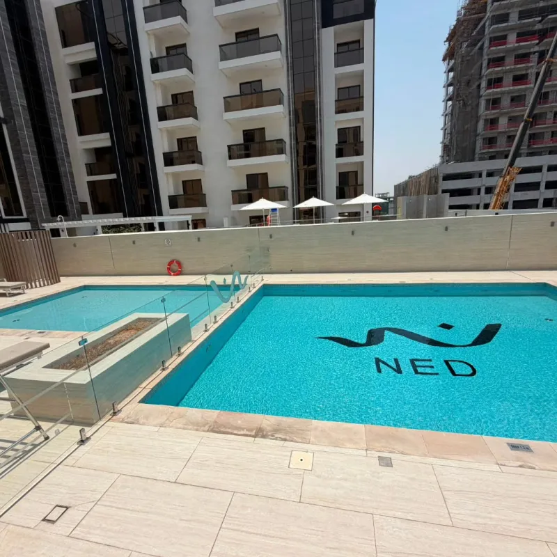A residential building pool with a dark mosaic motif set into the floor