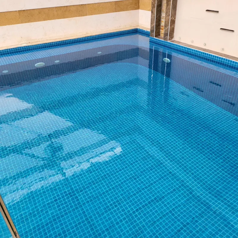 مسبح مجتمعي مبلّط بفسيفساء زرقاء بإطار رخامي