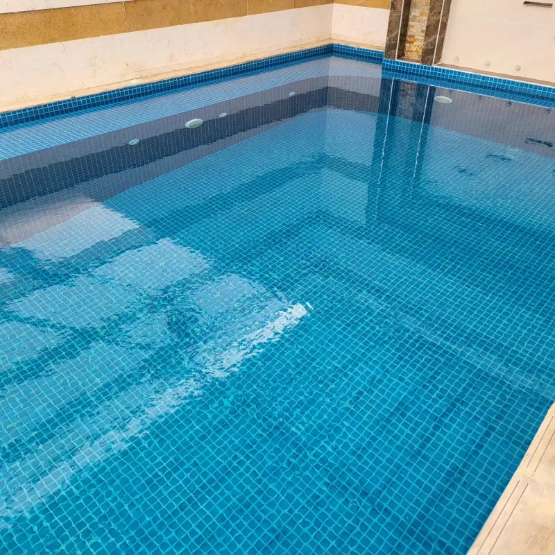مسبح مجتمعي مبلّط بفسيفساء زرقاء بإطار رخامي