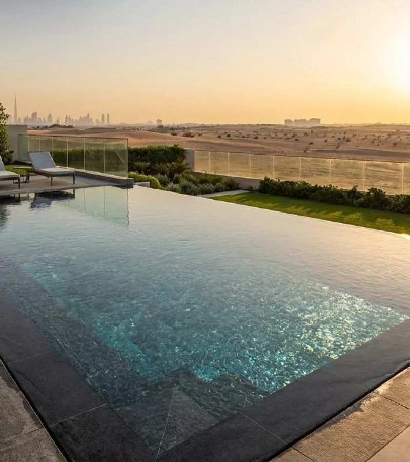 The same terrace after the upgrade, with a frameless glass balustrade, dark stone deck and an open view at sunset