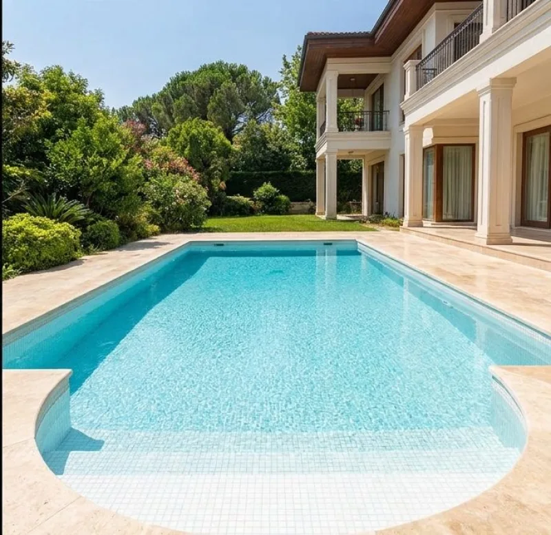 The same villa pool after cleaning and re-tiling, with clear blue water and a relaid stone surround