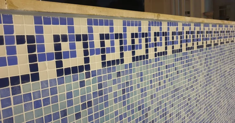 Glass mosaic tiling and a patterned border on a pool wall